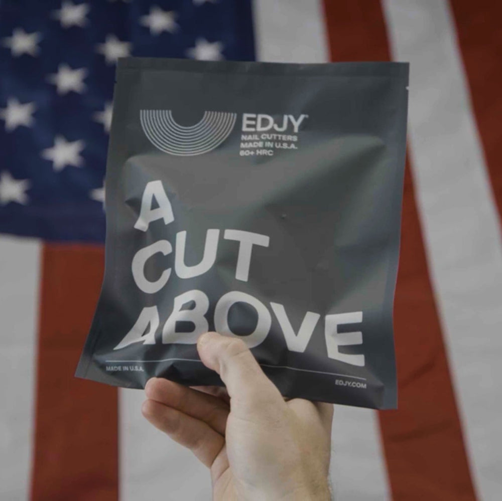 Hand holding a 'EDJY A Cut Above' package in front of an American flag